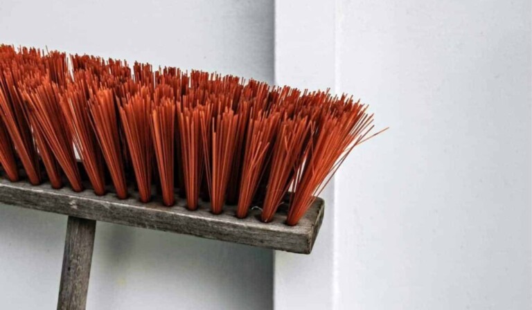 brown and orange push broom beside white wall