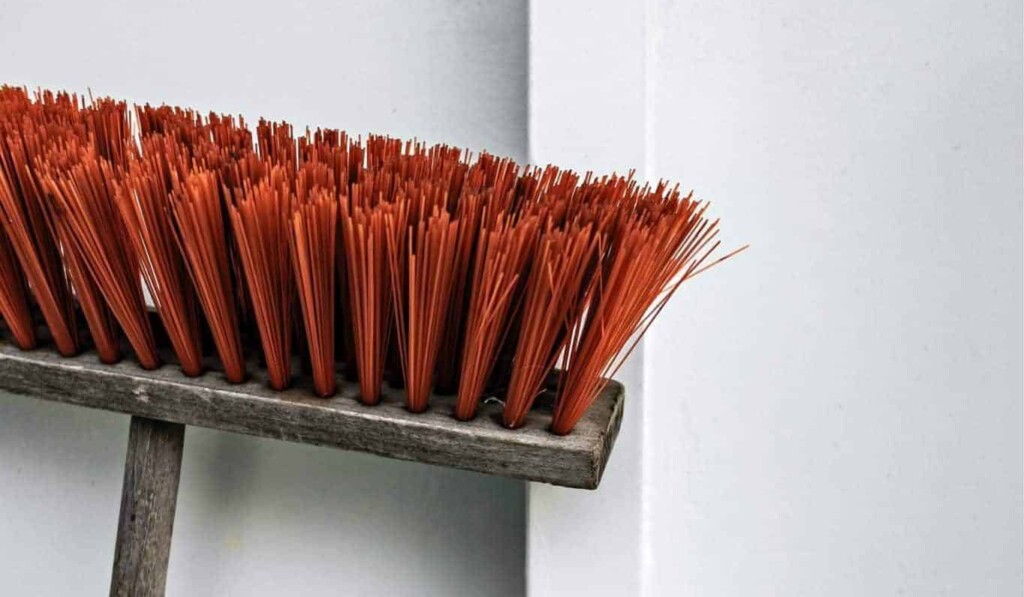 brown and orange push broom beside white wall