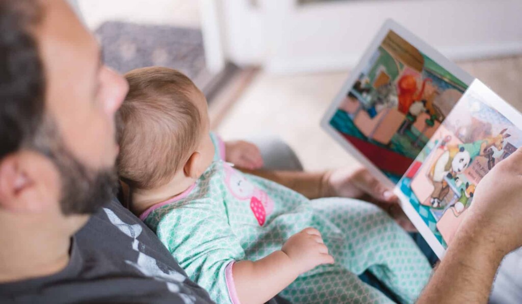person carrying baby while reading book