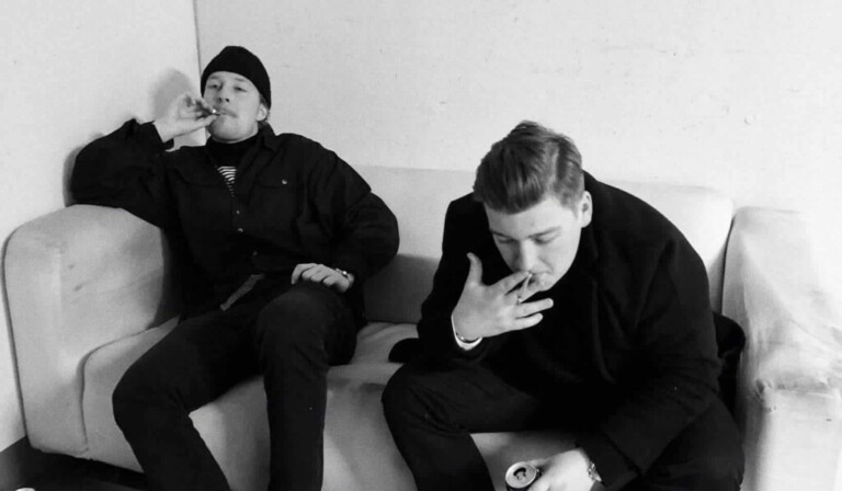 two men sitting on sofa grayscale photo