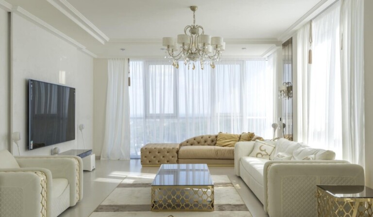 Interior of spacious room with huge windows behind curtains and comfortable furniture against TV set