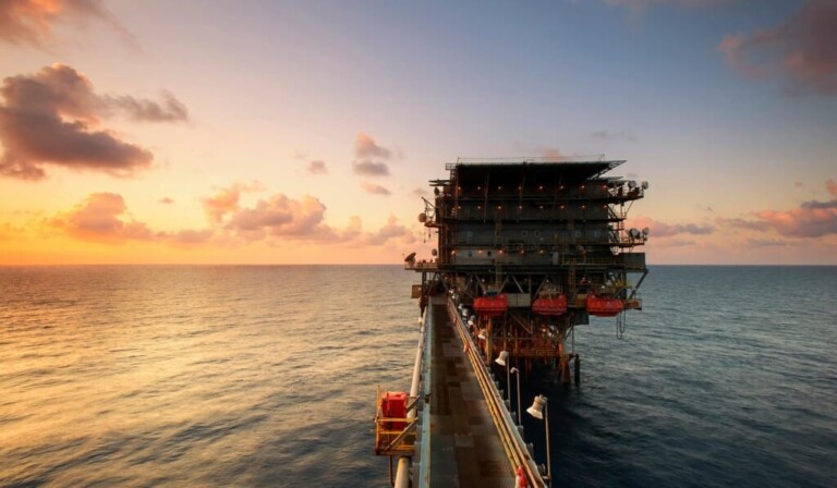 A breathtaking view of an oil platform on the ocean at sunset, showcasing industrial beauty.