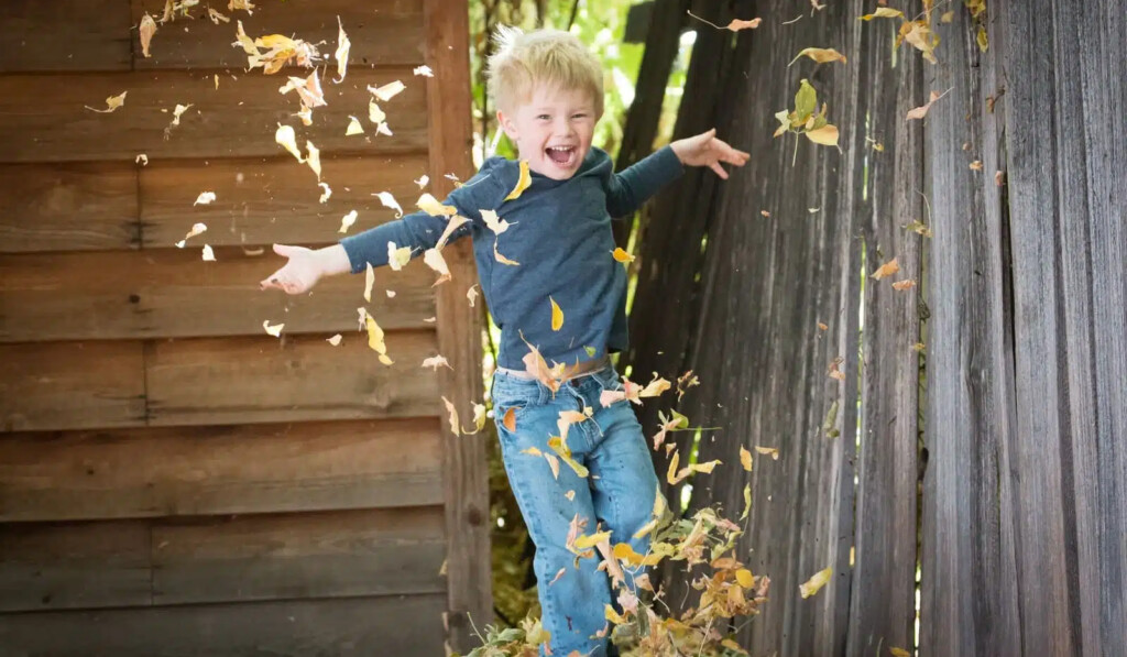 foto de un niño cerca de la valla con hojas caídas
