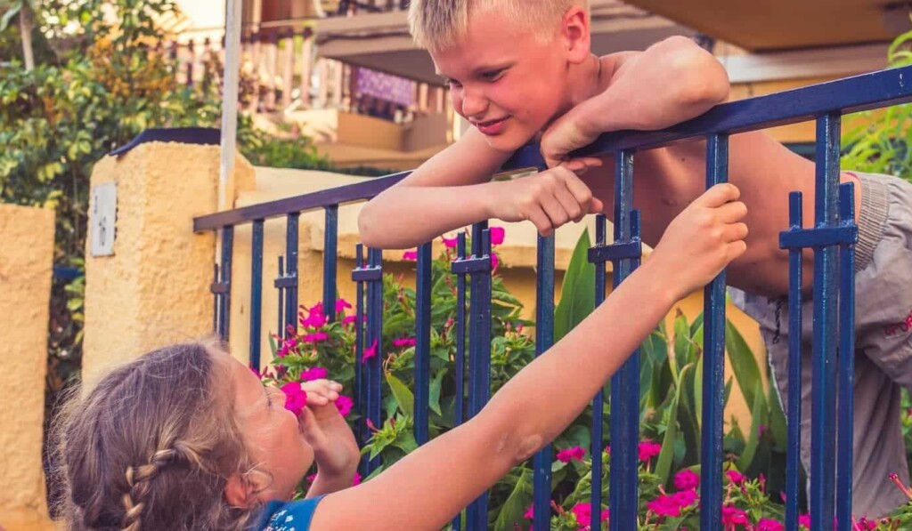 dekle v modro-beli cvetlični obleki, ki drži modro kovinsko ograjo