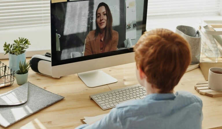 A child participating in an online class at home, focused on the educational content displayed on a desktop computer.